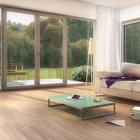 Modernes Wohnzimmer mit großer Glasfront, Parkettboden, Sofa und Blick in den Garten.