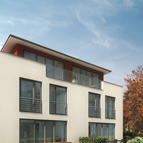 Modernes Mehrfamilienhaus mit großen Fenstern, Balkon und Garten bei blauem Himmel.